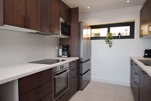 A modern kitchen with dark wood cabinets, stainless steel appliances, and a window with a view.