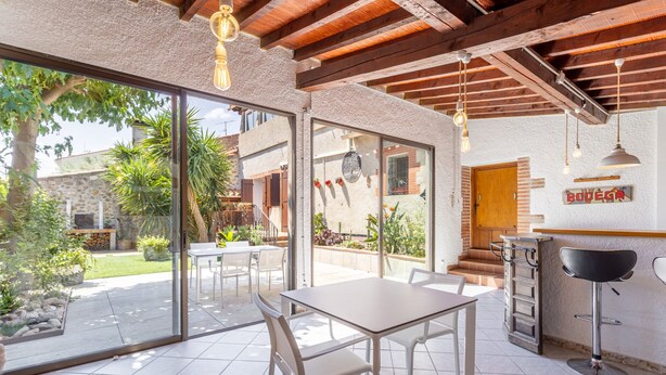 A modern kitchen with a bar area, large sliding glass doors, and a stone wall. - Holiday Home 'Lina' with Private Terrace, Wi-Fi and Air Conditioning (Villemolaque)