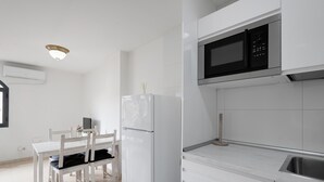 Une cuisine moderne avec des meubles blancs, un four à micro-ondes encastré et un évier en acier inoxydable.
