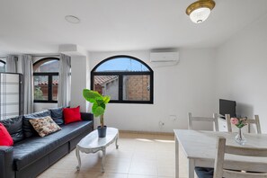 Un saló modern amb un sofà, una taula de centre, una taula de menjador i una planta en test.