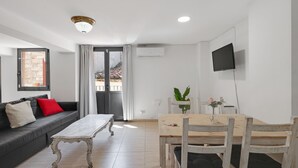A modern living room with a sofa, a wooden dining table, and a TV mounted on the wall. - Apartment 'Wonderful Loft Centre' with Balcony, Wi-Fi and Air Conditioning (Manresa)