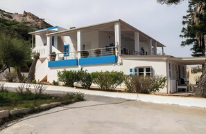 A two-story building with a balcony, a covered area, and a view of a hill. - Apartment 'No 2' with Sea View, Wi-Fi and Air Conditioning (Kos)