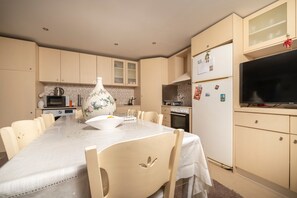 A modern kitchen with a dining table, chairs, a large vase, and a refrigerator with magnets. - Apartment 'No 2' with Sea View, Wi-Fi and Air Conditioning (Kos)