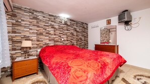 A bedroom with a bed, a nightstand, a dresser, a mirror, and a wall with a patterned design.