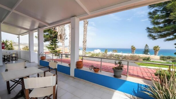 A covered outdoor area with a table and chairs, potted plants, and a view of the sea. - Apartment 'No 3' with Sea View, Wi-Fi and Air Conditioning (Kos)