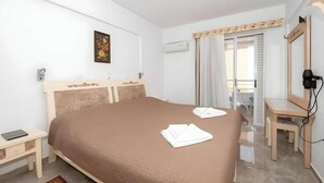 A bedroom with a bed, a desk, a chair, a mirror, and a window with curtains. - Apartment 'No 3' with Sea View, Wi-Fi and Air Conditioning (Kos)