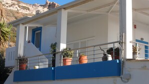 A building with a balcony, potted plants, and a blue door. - Apartment 'No 3' with Sea View, Wi-Fi and Air Conditioning (Kos)