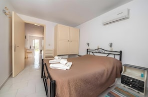 A bedroom with a bed, a nightstand, a wardrobe, and an air conditioning unit.