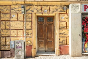 A building with a wooden double door, numbered 30, and a utility box with papers attached. - Apartment 'Amita' with Wi-Fi and Air Conditioning (Cagliari)