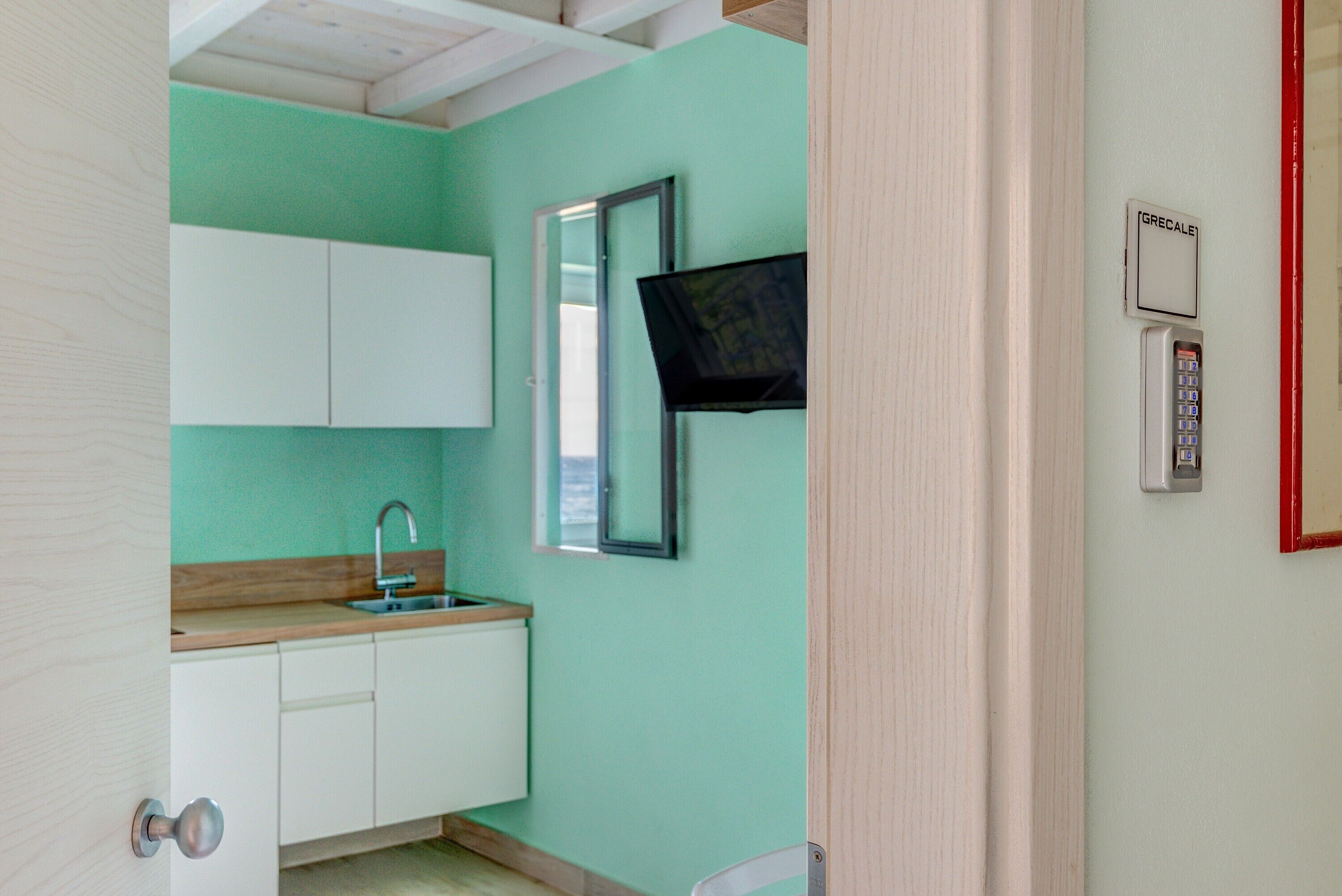 A kitchen with white cabinets, a sink, and a mounted television.