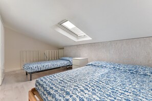 A bedroom with two beds, a skylight, a white bedside table, and a radiator. - Apartment 'Loft Scirocco' with Wi-Fi and Air Conditioning (Rio Marina)