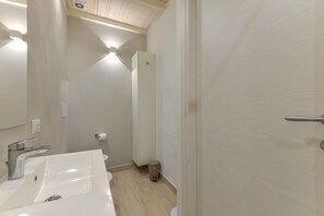 A bathroom with a white sink, mirror, and toilet. - Apartment 'Loft Scirocco' with Wi-Fi and Air Conditioning (Rio Marina)