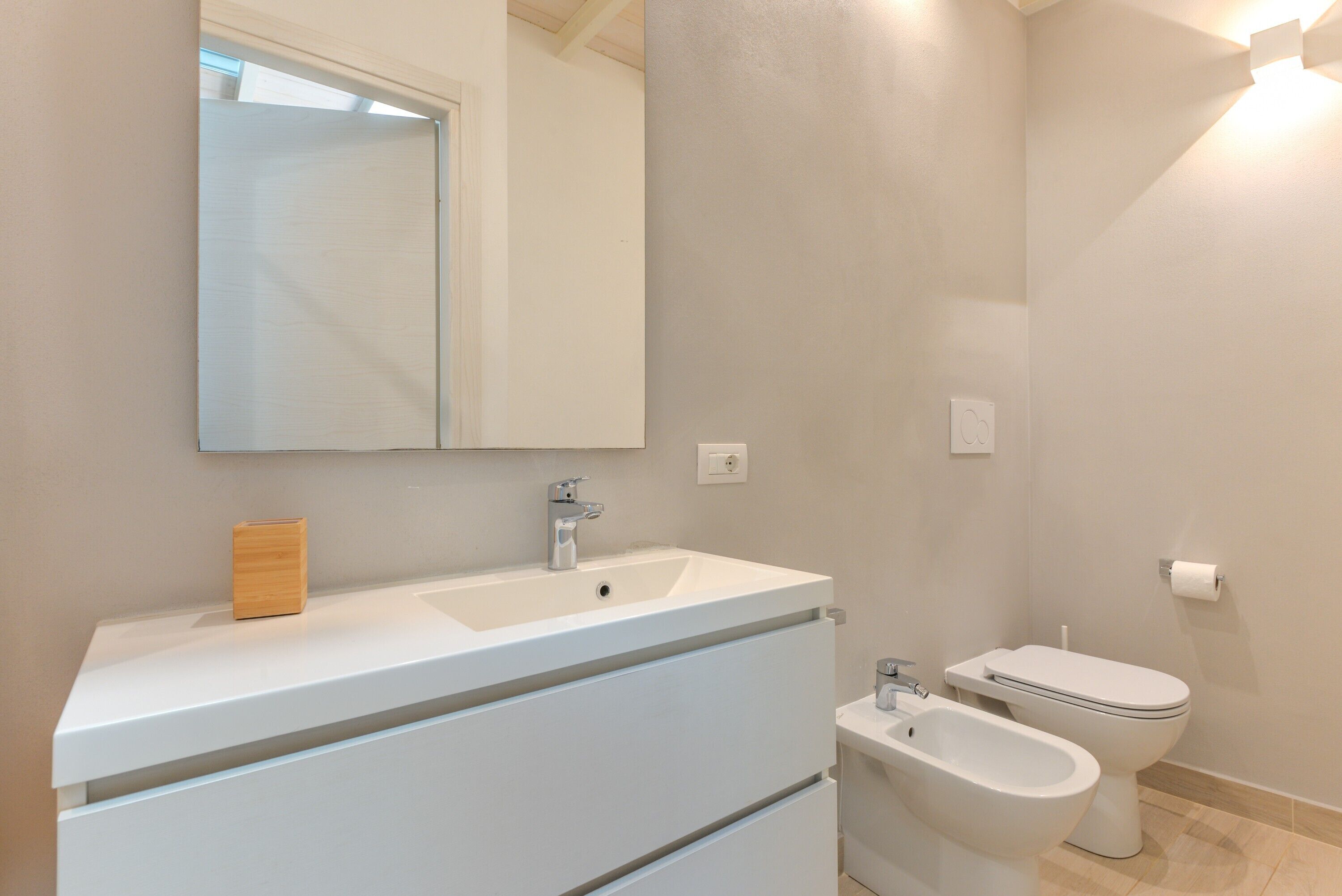 Une salle de bain avec un lavabo blanc, un miroir et un bidet.