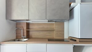Una cocina moderna con un lavamanos de acero inoxidable, encimera de madera y armarios blancos.