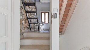Una escalera conduce a una habitación con pared de piedra, una ventana y una puerta con la leyenda 'MAESTRALE'.