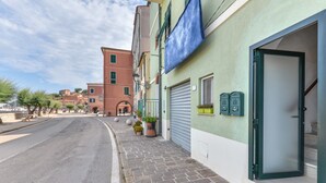 Vista de calle con edificios, una tienda cerrada con puerta verde y acera pavimentada.