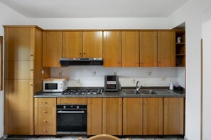 A kitchen with wooden cabinets, a microwave, a toaster, a sink, and an oven.