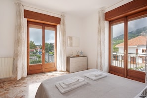 A bedroom with a bed, a dresser, and a view of the outside.