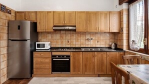 A kitchen with wooden cabinets, a stainless steel refrigerator, a microwave, a stove, and a sink.