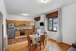 A kitchen with wooden cabinets, a refrigerator, a microwave, and a dining table with chairs.