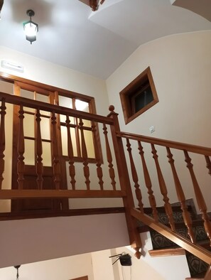A wooden staircase with a handrail, a small window, and a ceiling light fixture. - Room 'Triple Con Balcón' with Balcony and Wi-Fi (Villarluengo)