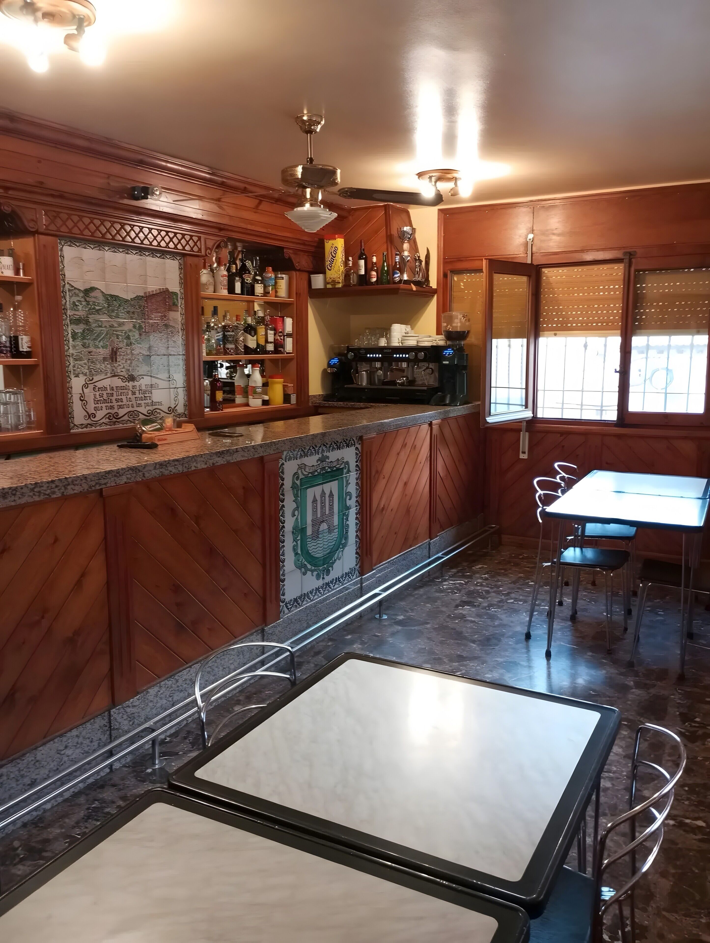 A bar area with wooden cabinets, a coffee machine, and a tiled backsplash.