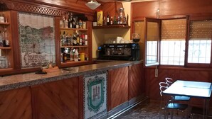 Un coin bar avec des meubles en bois, une machine à café et un mur recouvert de carreaux.