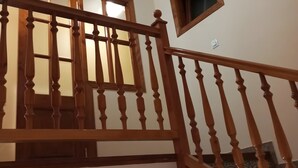 A wooden staircase with a handrail, a small window, and a ceiling light fixture.