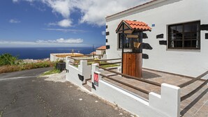 Una propiedad costera con fachada blanca, un portón de madera y vista al océano.