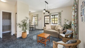 Un salón amplio con sofá, sillas, una mesa de centro y una mesa de comedor.