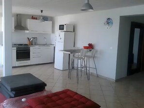 Une cuisine moderne avec des meubles blancs, un four à micro-ondes et un réfrigérateur. Il y a également un coin repas avec une table et des chaises.