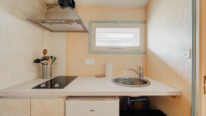 A compact kitchenette with a stove, sink, and window.