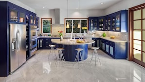 A modern kitchen with blue cabinets, a central island with stools, stainless steel appliances, and a large window providing natural light. - Modern Santa Rosa Retreat Near Wineries & Trails (Santa Rosa)