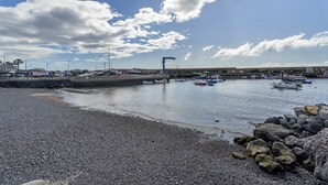 Una playa de guijarros con barcos amarrados al fondo.