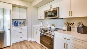 A modern kitchen with white cabinetry, stainless steel appliances, and a wooden floor. - Private Pool + Putting Green: Sunny Scottsdale Gem (Scottsdale)