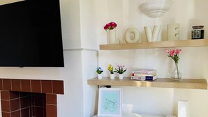 A living room with a flat-screen TV mounted on the wall, a fireplace with a tiled surround, and a white dresser with drawers. - Vauxhall, river Thames, Big Ben Retreat, Central London family Stay (London)