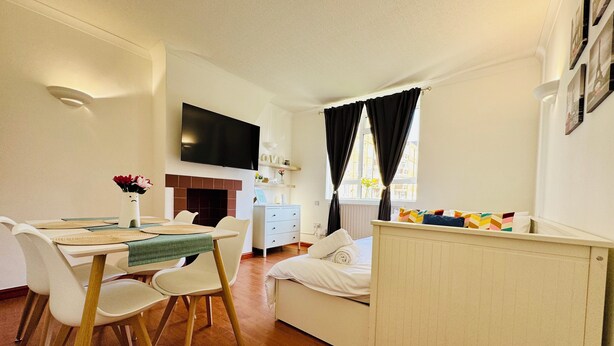 A modern, well-lit room with a dining area, a sofa, a TV, and a window with curtains. - Vauxhall, river Thames, Big Ben Retreat, Central London family Stay (London)
