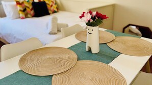 A neatly arranged hotel room with a dining table set with placemats, a vase with flowers, and a bed with pillows in the background. - Vauxhall, river Thames, Big Ben Retreat, Central London family Stay (London)