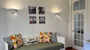 A cozy room with a white sofa bed, a green throw, and four wall-mounted pictures of Paris landmarks. - Vauxhall, river Thames, Big Ben Retreat, Central London family Stay (London)