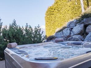 Een hottub met uitzicht op een berg en bomen.