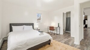 A modern bedroom with a large bed, bedside tables, a desk, and a chair.