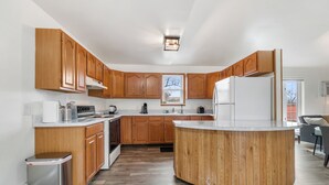 A modern kitchen with wooden cabinets, a central island, and a built-in stove.