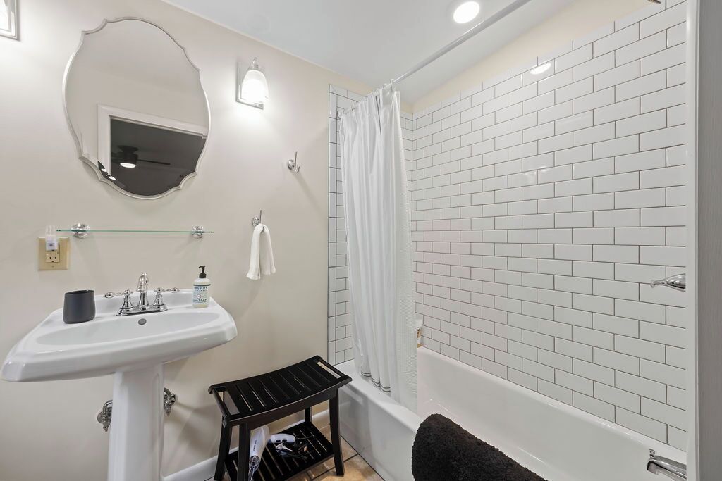 Un baño con un lavabo blanco, un espejo, una ducha con cortina y una bañera.