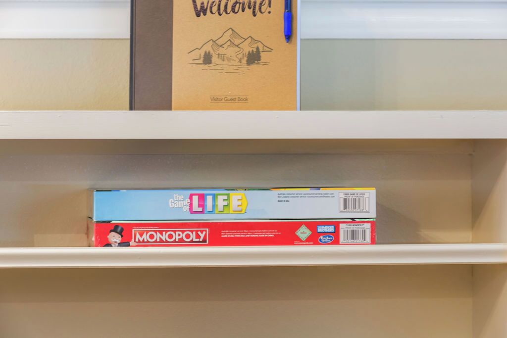 A shelf with a welcome sign and a Monopoly board game.