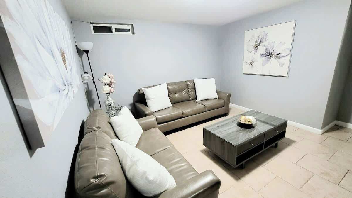 A living room with a sofa, a coffee table, and a vase with flowers.