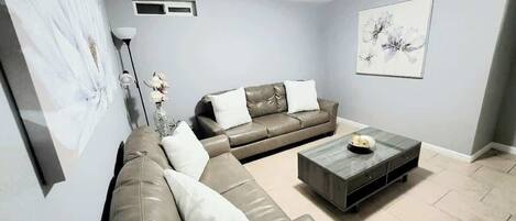 A living room with a sofa, a coffee table, and a vase with flowers.