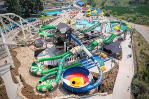 A water park with a roller coaster, multiple water slides, and a pool area. - $0Fees -6BR-2Kitchen-2LivRm-Easy to RedRocks/Dtown (Denver)