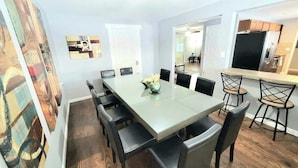 A dining area with a long table, black chairs, and a vase with flowers. - $0Fees -6BR-2Kitchen-2LivRm-Easy to RedRocks/Dtown (Denver)