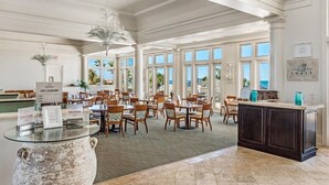 A spacious dining area with high ceilings, large windows, and a central island with a glass top.