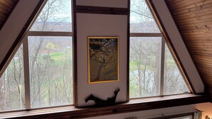 A room with high ceilings, wooden beams, and large windows offering a view of trees and a distant house. - 474, Your Mountain Getaway. (Keyser)